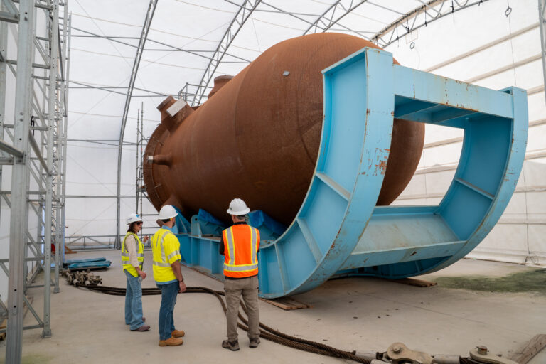 Workers examine a large component and the Fairfield nuclear site. 